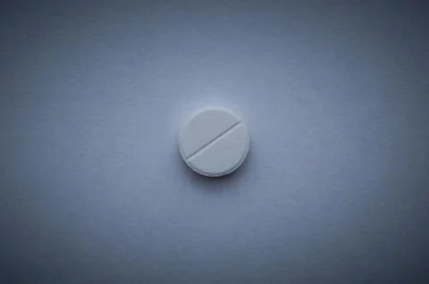One white large pill on a dark blue background. Stock Photos
