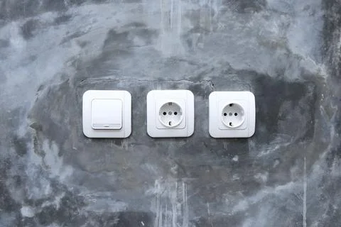 One white light switch and two electrical outlets mounted on a raw polished.. Stock Photos