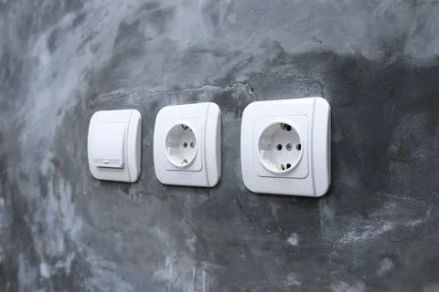 One white light switch and two electrical outlets mounted on a raw polished.. Stock Photos