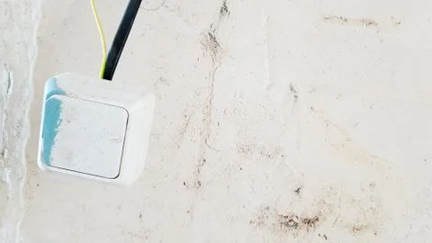 One white light switch in paint and putty is temporarily hanging on a black w Stock-Fotos