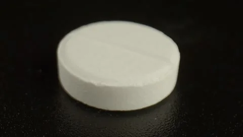One white pill on a dark background. The solid dosage form contains several Stock Footage 164230492