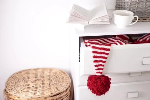 One white-red hat with a large red pompom hangs from an open drawer of a whit Foto stock