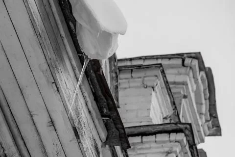 One white snowdrift with a sharp transparent icicle is hanging down from the Fotos Stock