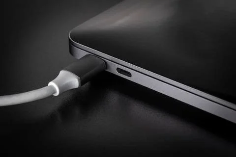 One white USB type C cable connected to laptop Stock Photos