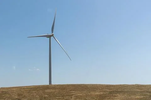 One white wind generator produces alternative energy by wind on the field Stock Photos