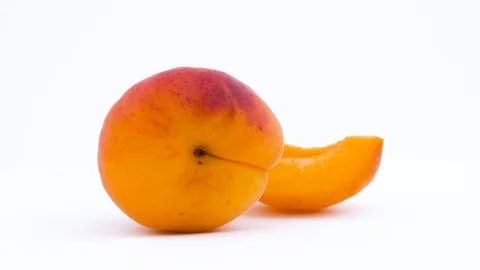 One whole and one slice of apricot fruit. Rotating on the turntable. Isolated Stock Footage 92924635