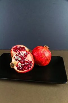 One whole and two half pomegranates. Stock Photos