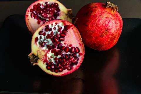 One whole and two half pomegranates. Stock Photos