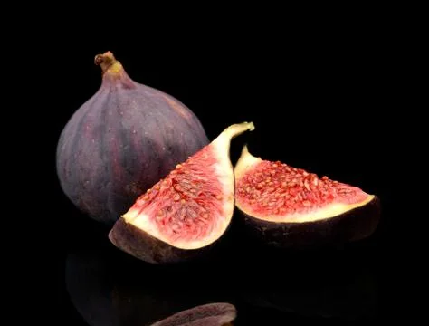 One whole fig and two quarters of figs isolated on black background Stock Photos