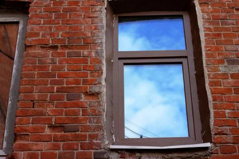 One window in a modern brown plastic frame in an old red orange brick building Stock Photos