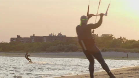 As one windsurfer plies the water, another tests out his gear on the Stock Footage 243173310