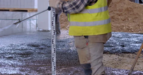 One worker align cement screed, another checks a surface level and makes a mark Stock Footage 147636019