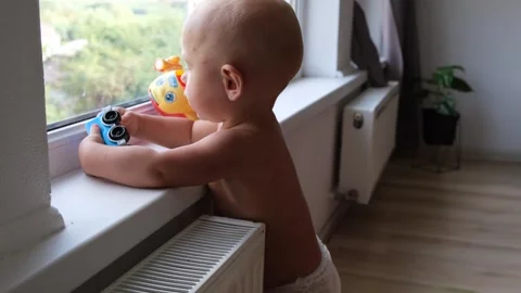 One year old baby boy playing with toys standing near the window on the Stock Footage 249590430