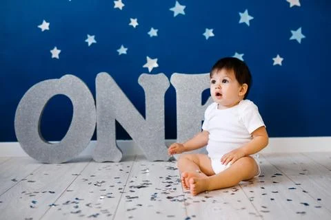 One year old baby boy in white t-shirt celebrates first birthday near silve.. Stock Photos