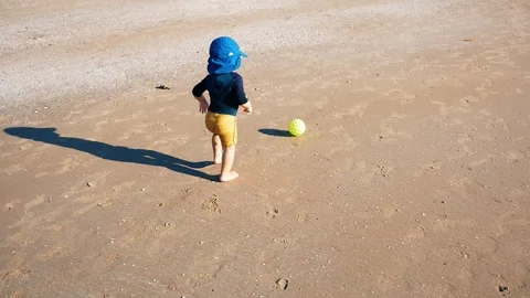 A one year old baby playing with a ball on the beach Stock Footage 123386997
