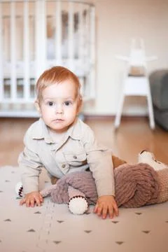 A one-year-old boy in a beige shirt and sitting on the floor Stock Photos