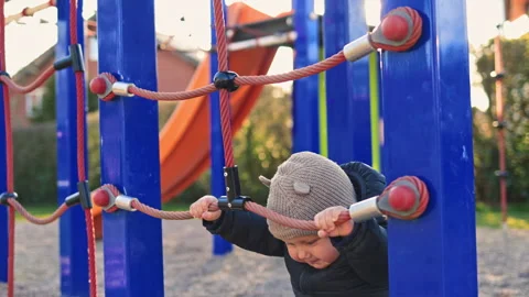 One year old boy in a black jacket runs and plays outside on the playground Stock Footage 319928730