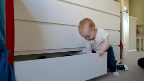 One year old  boy opens the dresser drawer and pulls  out of the drawer shoes Stock Footage 270198944