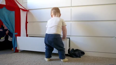 One year old  boy opens the dresser drawer and pulls everything out of the dr Stockbeeldmateriaal 271319076