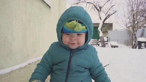 One year old boy plays in the snow yard Видео 98898083