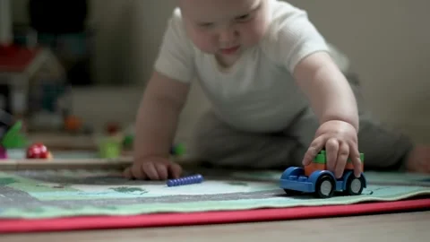 One year old boy plays with a car on the floor, close-up Stock Footage 272563777