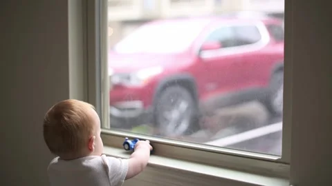 One year old boy plays with the car toy  on the windowsill ,  childhood fun,  Vídeo Stock 272563873