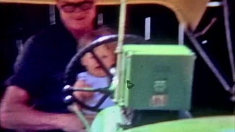 One year old boy riding big tractor with adult Stock Footage 194521839