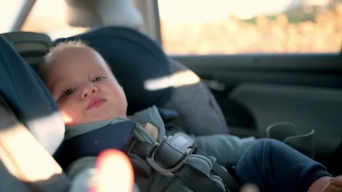 The one year old boy is sitting in the car seat, looking out the window, angr Stock Footage 271457288