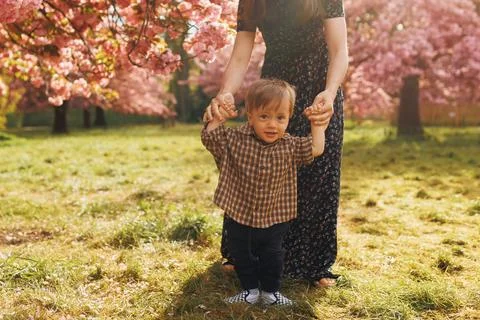One-year-old boy smiling at the camera while his mother holds his hands Stock Photos