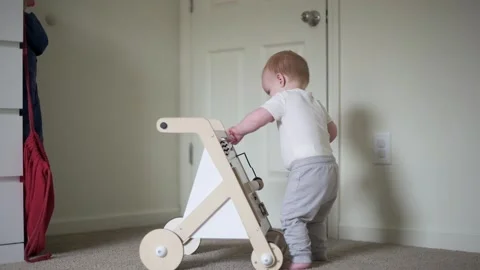 A one year old boy standing carefully in the room plays with a montessori edu Vidéo 273438599