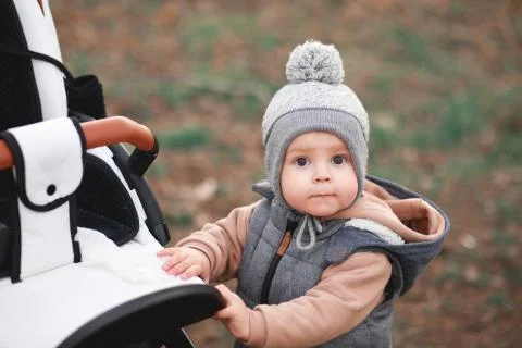 A one-year-old boy taking some of his first steps outdoors on a track with se Stock Photos