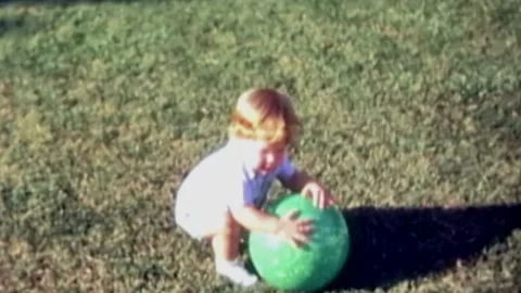 One year old boy trying to pick up ball in backyard Stock Footage 194521731