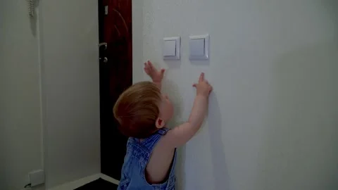 A one-year-old boy turns off the light in the apartment by pressing the wall swi Stock Footage 308870554