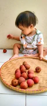One Year Old Child Discovering Lychee Fruits on Porch Foto stock
