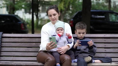 A one-year-old child sits in his mother's arms and watches cartoons in the autum Stock Footage 210854341