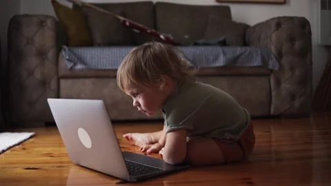A one-year-old child is sitting in front of a laptop. Funny little kid is Stock Footage 226764095