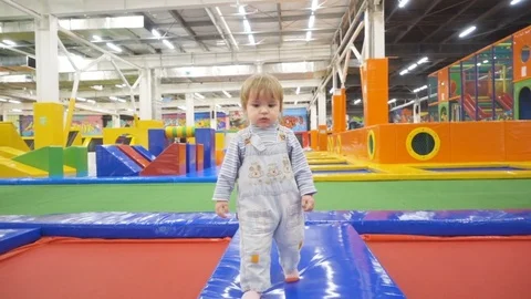The One Year Old Cute  is Making His First Steps In Indoors Playground. Act.. Video stock 72432773