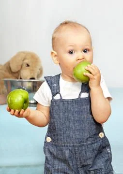One year old kid eats a green apple. Foto stock