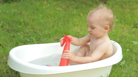 One year old kid having a bath outdoors Stock Footage 64739029