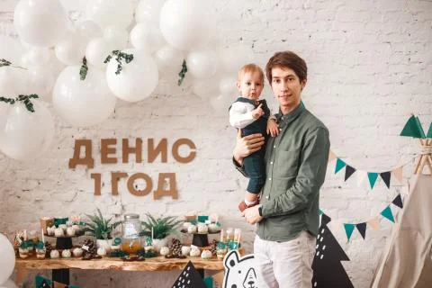A one-year-old son sits in the arms of a young father Stock Photos