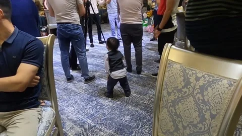 One year old Uzbek boy in small vest suit dancing at birthday party Stock Footage 336506597