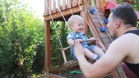 One years-old baby boy with blue eyes play on the swing outdoor Stock Footage 67355437