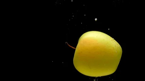 One yellow apple are falling into transparent water on black background Video stock 108783637