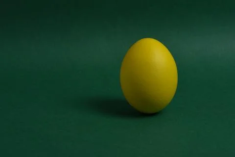 One yellow painted Easter egg stand on a green background. Stock Photos