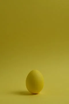 One yellow painted Easter egg stand on a yellow background. Фото