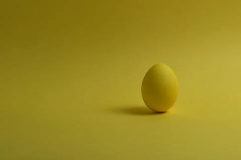 One yellow painted Easter egg stand on a yellow background. Stock Photos