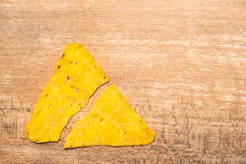 One yellow triangular nachos broken in half. Fast food and high-calorie food Stock Photos