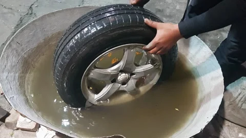 One young adult worker checking the tire puncture of a car in water tub. Stock Footage 341164507