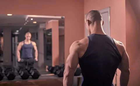 One young bodybuilder back looking in mirror, looking at self, rear view, upp Stock Photos