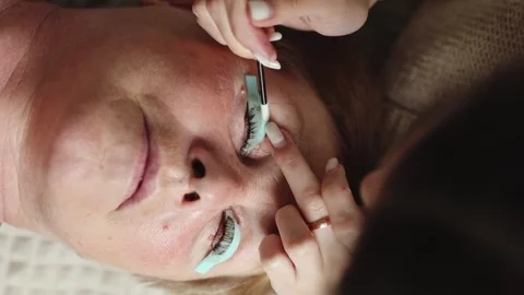 One young cosmetologist laminates the eyelashes of an elderly woman. Video stock 300809328